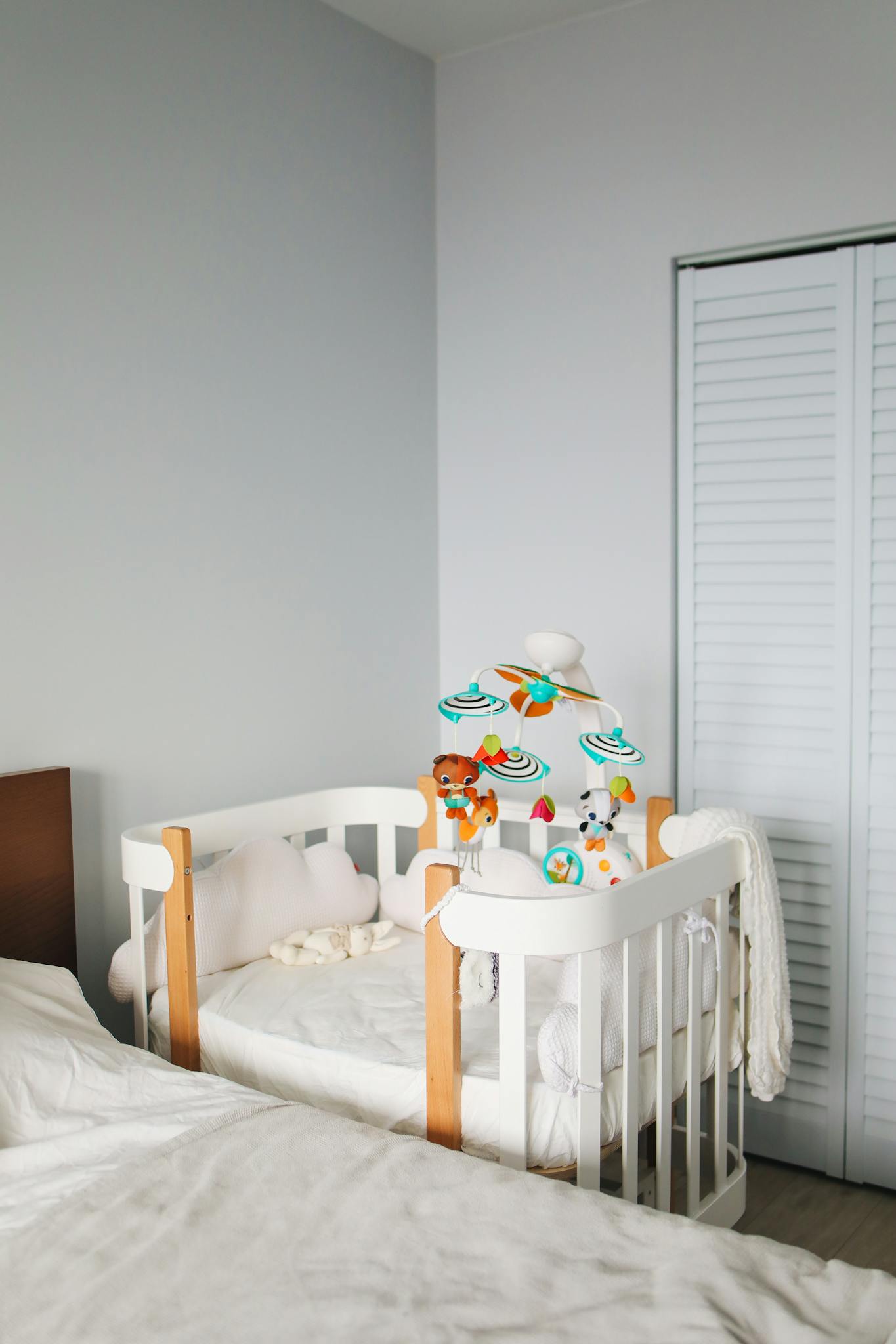 A bright and cozy nursery corner featuring a white crib with soft toys and minimalist decor.