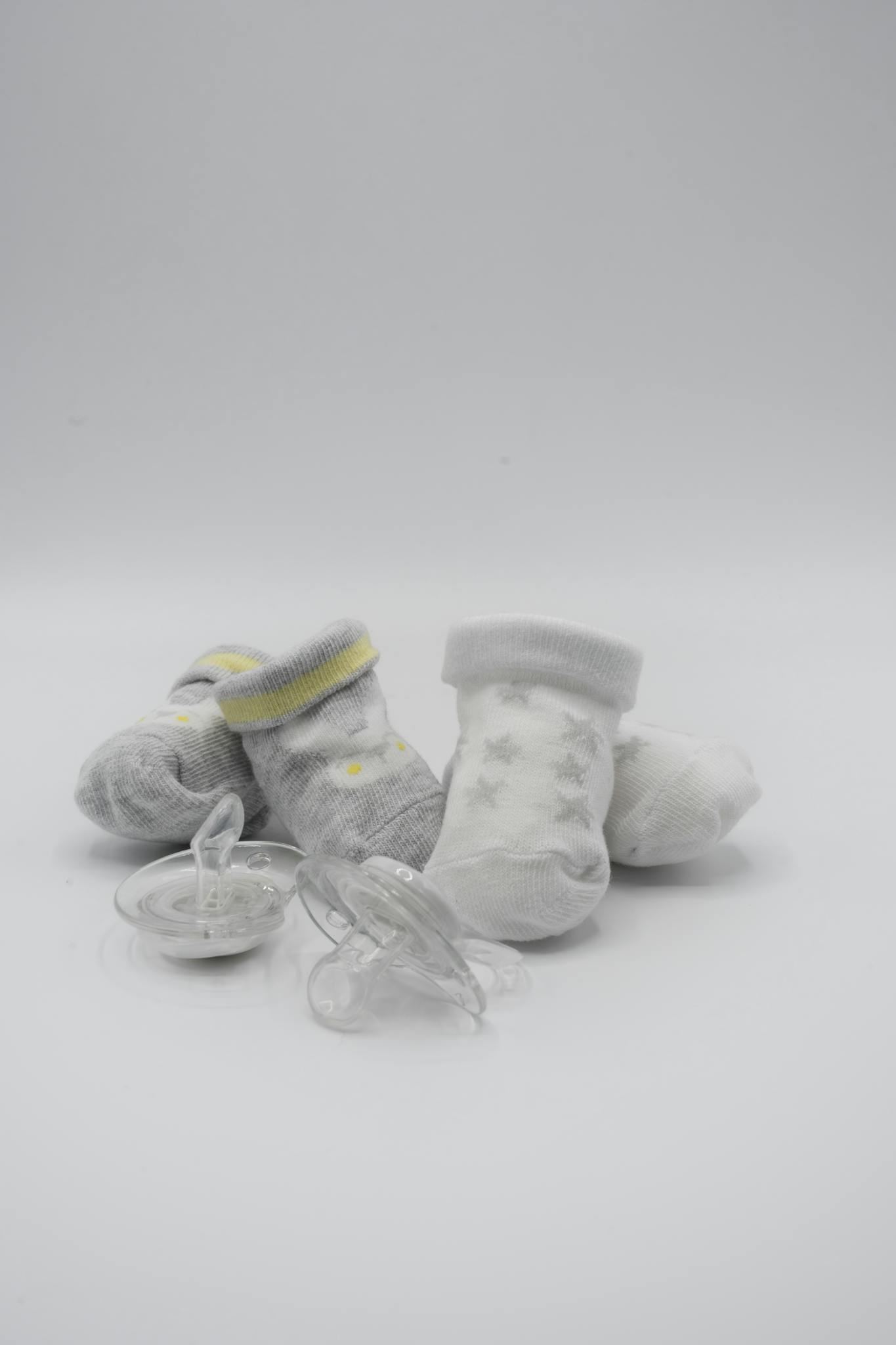 Adorable baby socks and pacifiers on a clean white surface, perfect for newborn essentials.